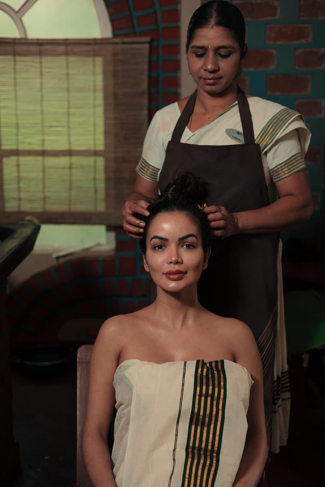A therapist preparing a patient for Shiro Abhyangam, a head therapy with warm oil