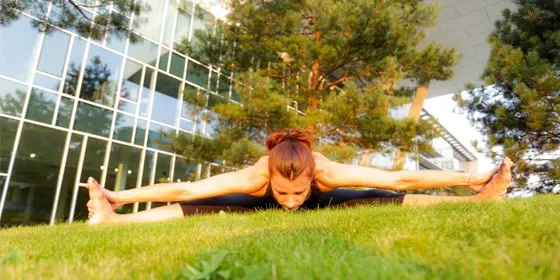 Flexion avant de yoga sur une pelouse