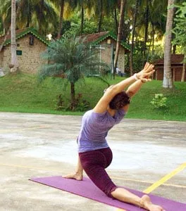 Una persona che pratica yoga all’aperto accanto ad alcuni cottage.