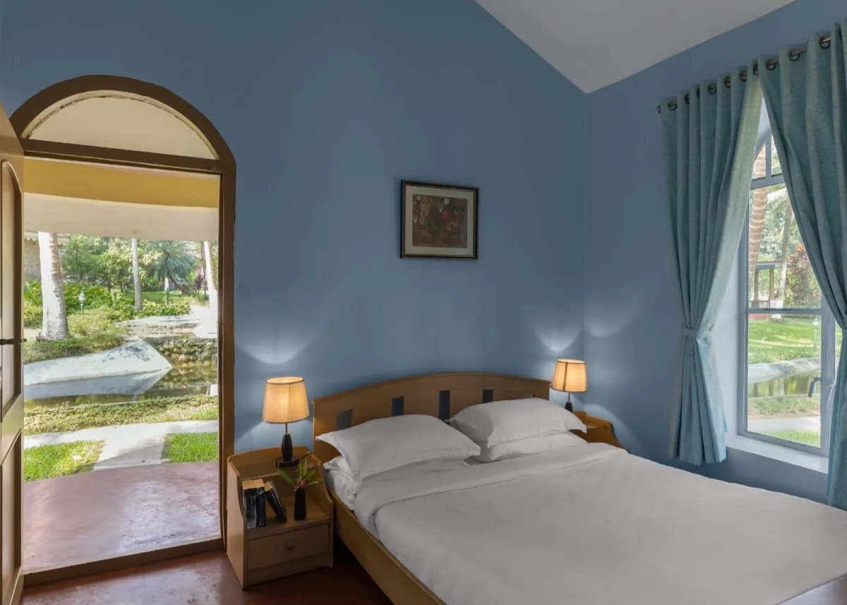 Slaapkamer van een blauwe Deluxe Villa naast een deuropening naar de tuin
