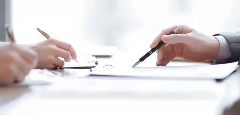 机で書類を確認し署名する2人の人物