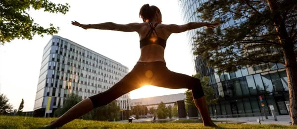 Una persona che esegue una posizione yoga in piedi all'aperto.