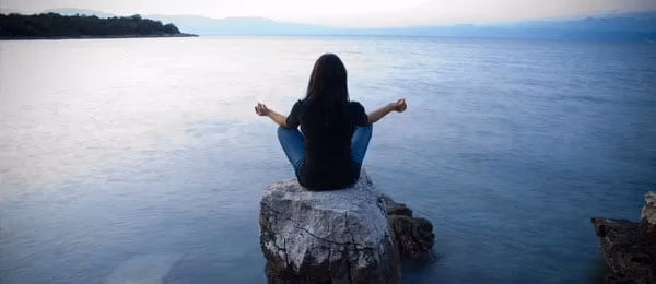 A person seated by the water.