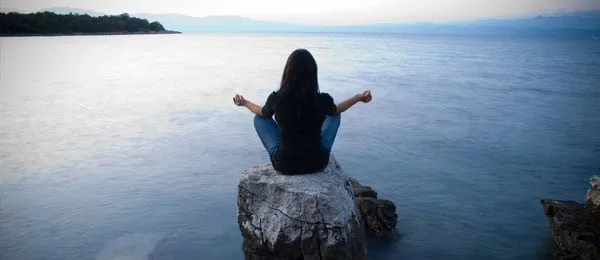 Una persona seduta vicino all'acqua.