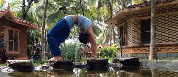 A person practising a backbend outside cottages.