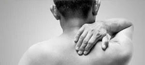 Immagine in bianco e nero di un uomo che porta la mano all'indietro per stringersi il collo e la spalla
