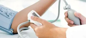 Un operatore sanitario misura la pressione sanguigna di un paziente con bracciale e pompetta manuale