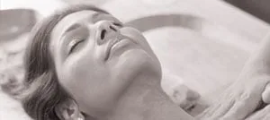 Primo piano color seppia di una donna sdraiata con gli occhi chiusi e la testa reclinata all'indietro