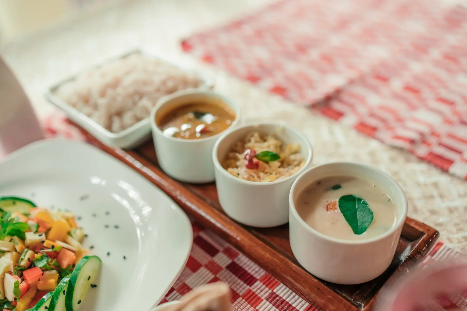 素食餐盘斜角视图：红米饭；sambar（扁豆蔬菜汤）；thoran（椰丝炒蔬菜）和以咖喱叶点缀的椰奶炖菜