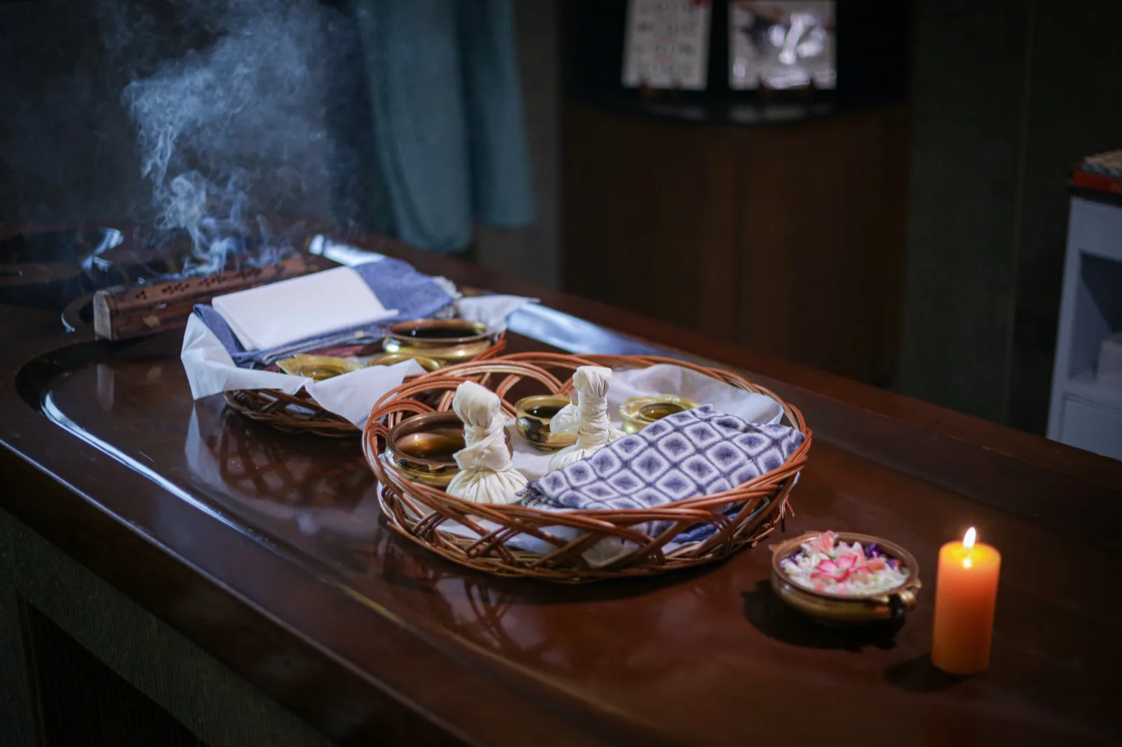 治疗准备静物：木质治疗床上的柳条篮中盛放着草药包（kizhi）；盛有草药油的黄铜碗