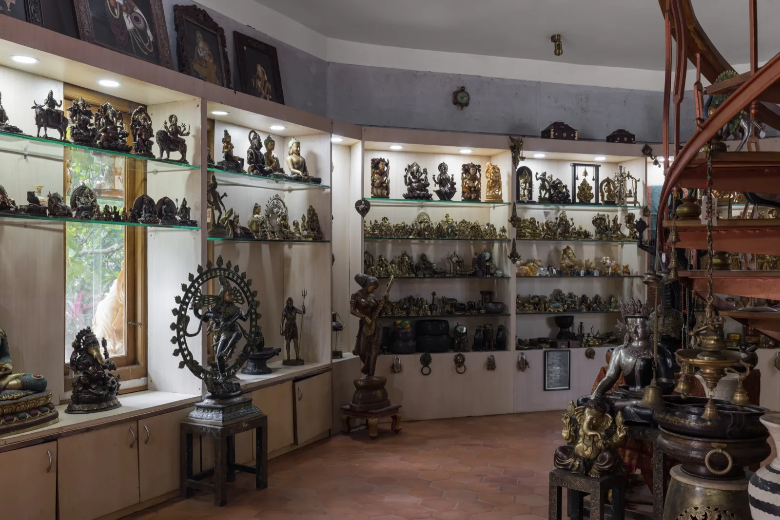 Interno del negozio di oggetti d'arte e artigianato con scaffali di statuette di divinità in bronzo e ottone, tra cui Nataraja; statue di Ganesha e del Buddha