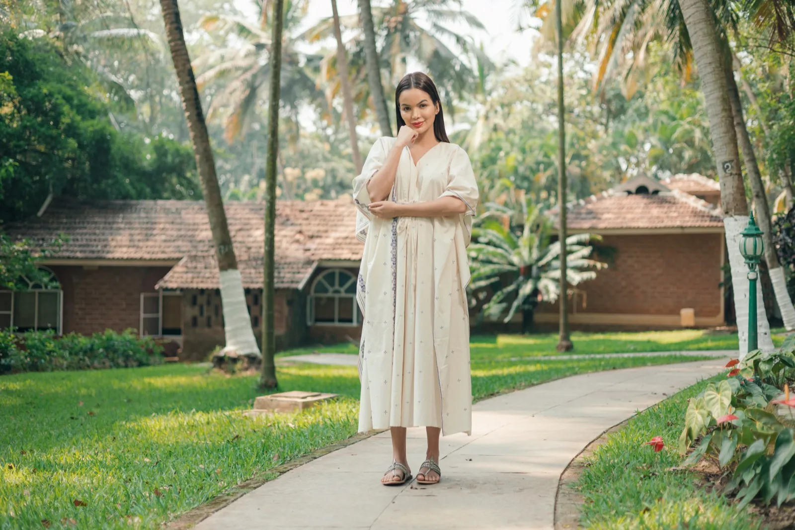 لقطة كاملة لامرأة واقفة على ممر مرصوف منحنٍ بين المروج