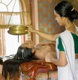 Trattamento ayurvedico con olio e recipiente sospeso