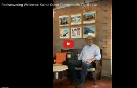 'स्वास्थ्य की पुनर्खोज: Kairali के रोगियों के प्रशंसापत्र जो आपको पसंद आएँगे' शीर्षक वाला वीडियो, फ़्रेम की गई तस्वीरों के नीचे बैठा एक व्यक्ति