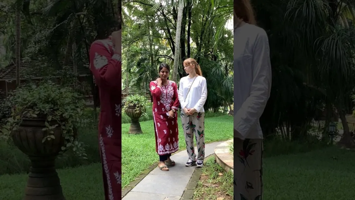两位女士在棕榈树与草坪间的铺砌花园小径上交谈
