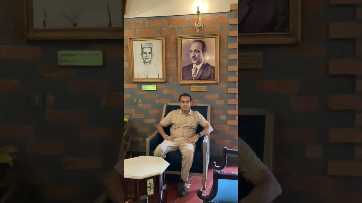رجل جالس على كرسي بذراعين أسفل صورتين مؤطّرتين على جدار من الطوب المكشوف