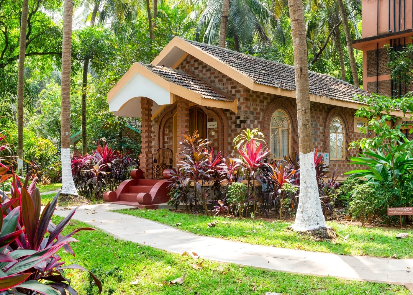 The Classic Villa: a brick cottage with a tiled roof and arched veranda, set among red-leaved plants